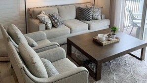 Un salon confortable avec un canapé, des fauteuils, une table basse et un ventilateur de plafond.