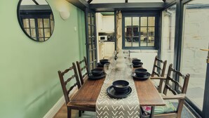 Comedor con una larga mesa de madera dispuesta para seis personas, rodeada de sillas de madera.