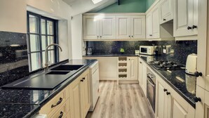Una cocina moderna con armarios blancos, encimeras negras y un tragaluz.
