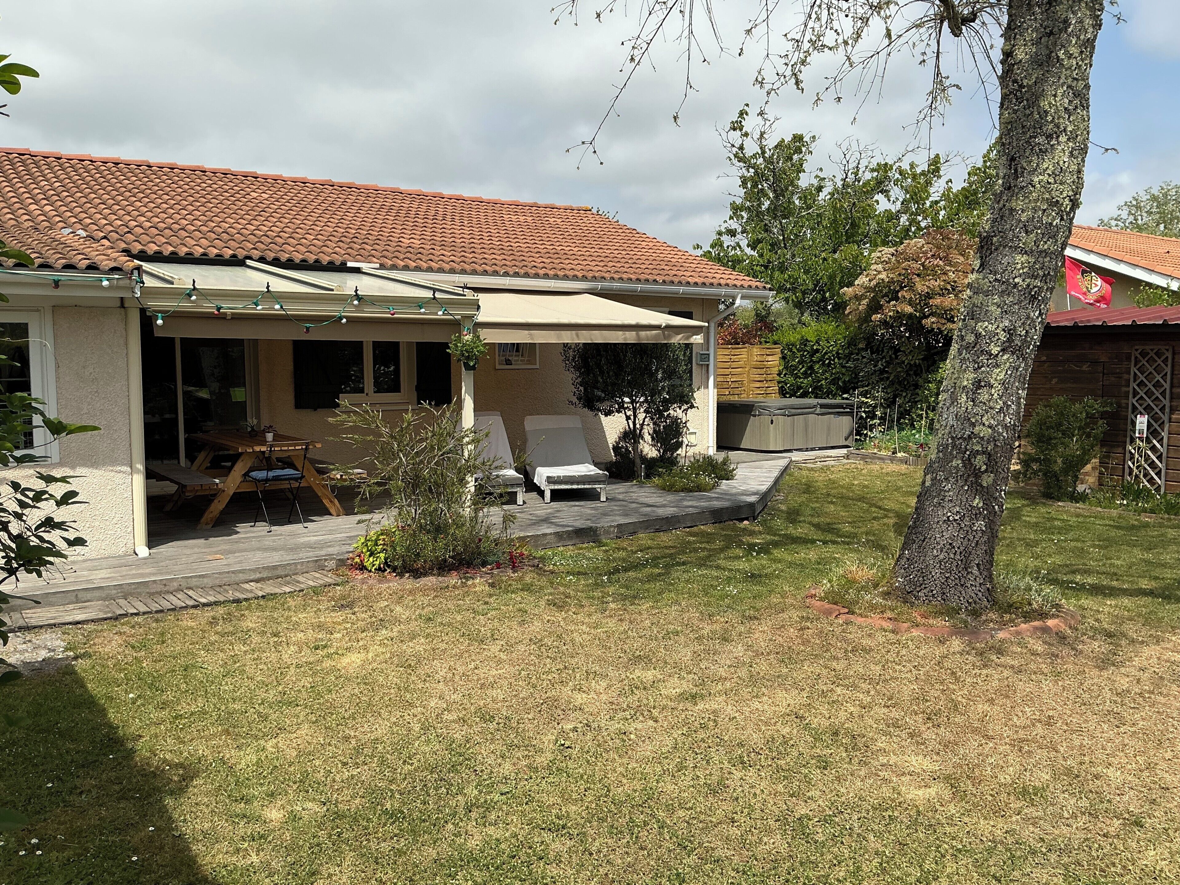 Une maison dotée d’un patio couvert, d’un jacuzzi et d’une pelouse.