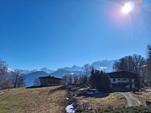 Eine Berglandschaft mit blauem Himmel, einigen Gebäuden und einem Weg, der bergauf führt.