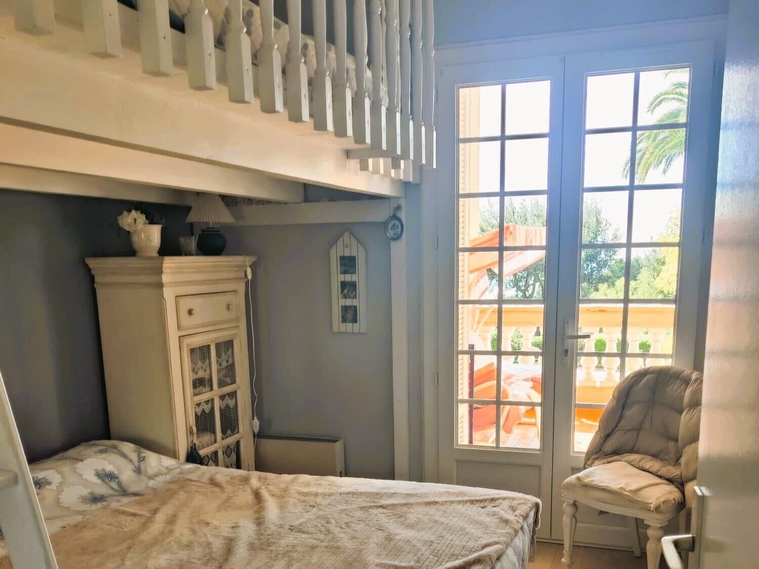A bedroom with a bed, a chair, a dresser, and a window with a view of the outdoors.