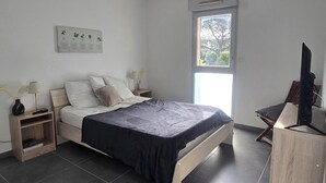 A bedroom with a bed, bedside tables, a TV, and a window. - Saint-Raphaël: Apartment Near Beach & Pool (Saint-Raphaël)