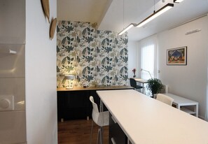 Eine moderne Küche mit weißer Arbeitsplatte, einem Holzespeisetisch und einem Wandpapier mit Muster.