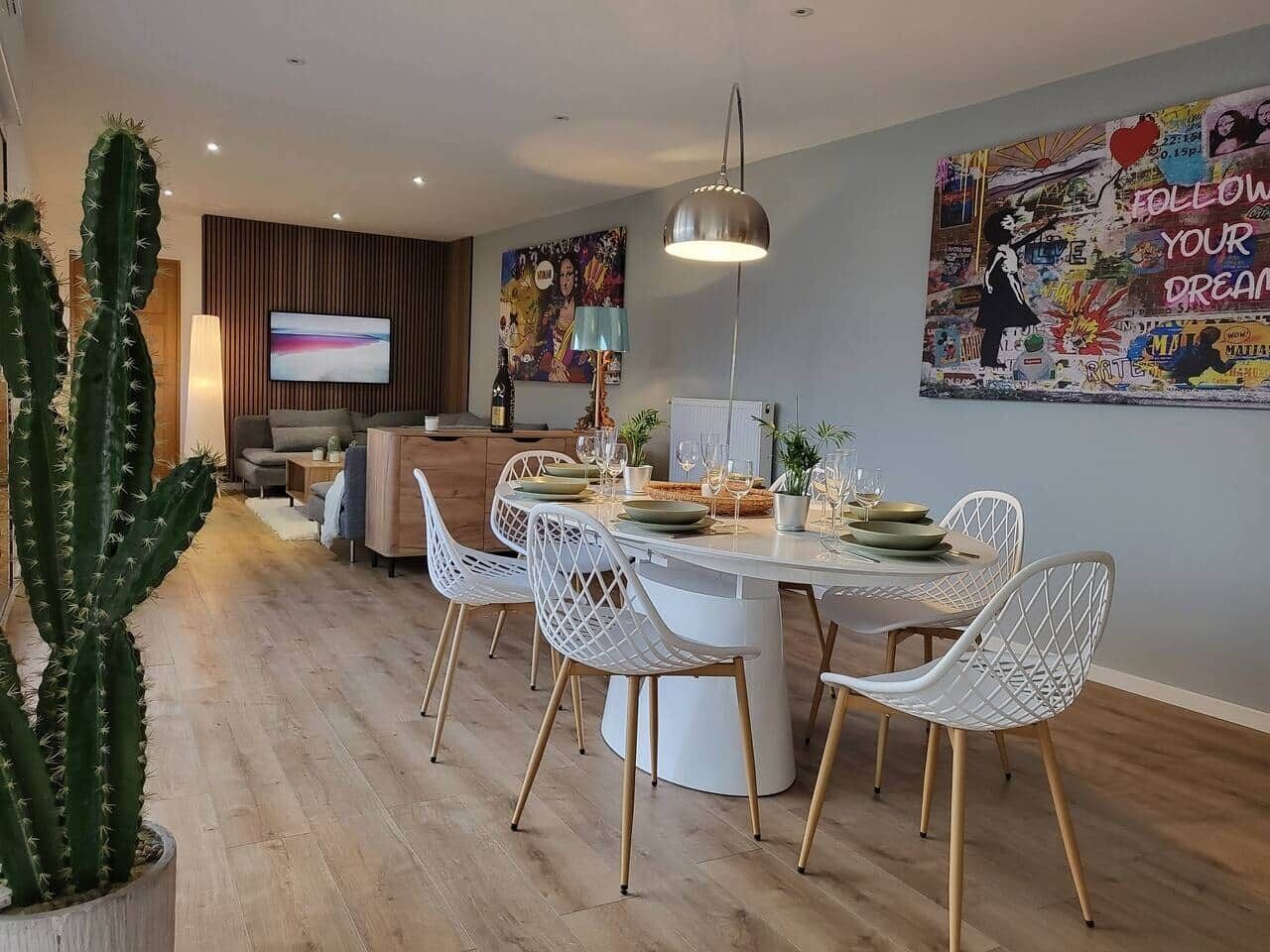 A modern dining area with a round table, white chairs, and a pendant light.