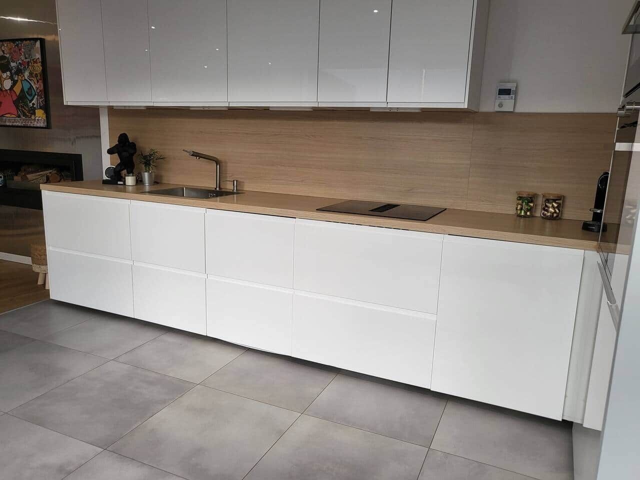 Een moderne keuken met witte kasten, een houten aanrechtblad en een inbouwgootsteen.
