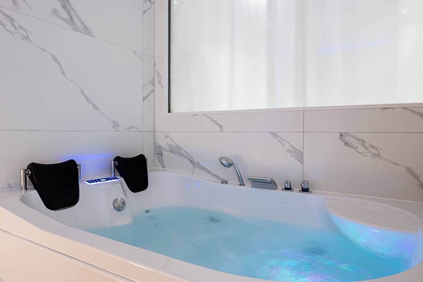 Un baño moderno con una bañera independiente, un cabezal de ducha manual y un asiento integrado.