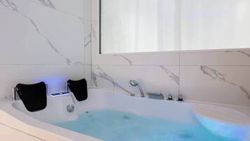 Un baño moderno con una bañera independiente, un cabezal de ducha manual y un asiento integrado.