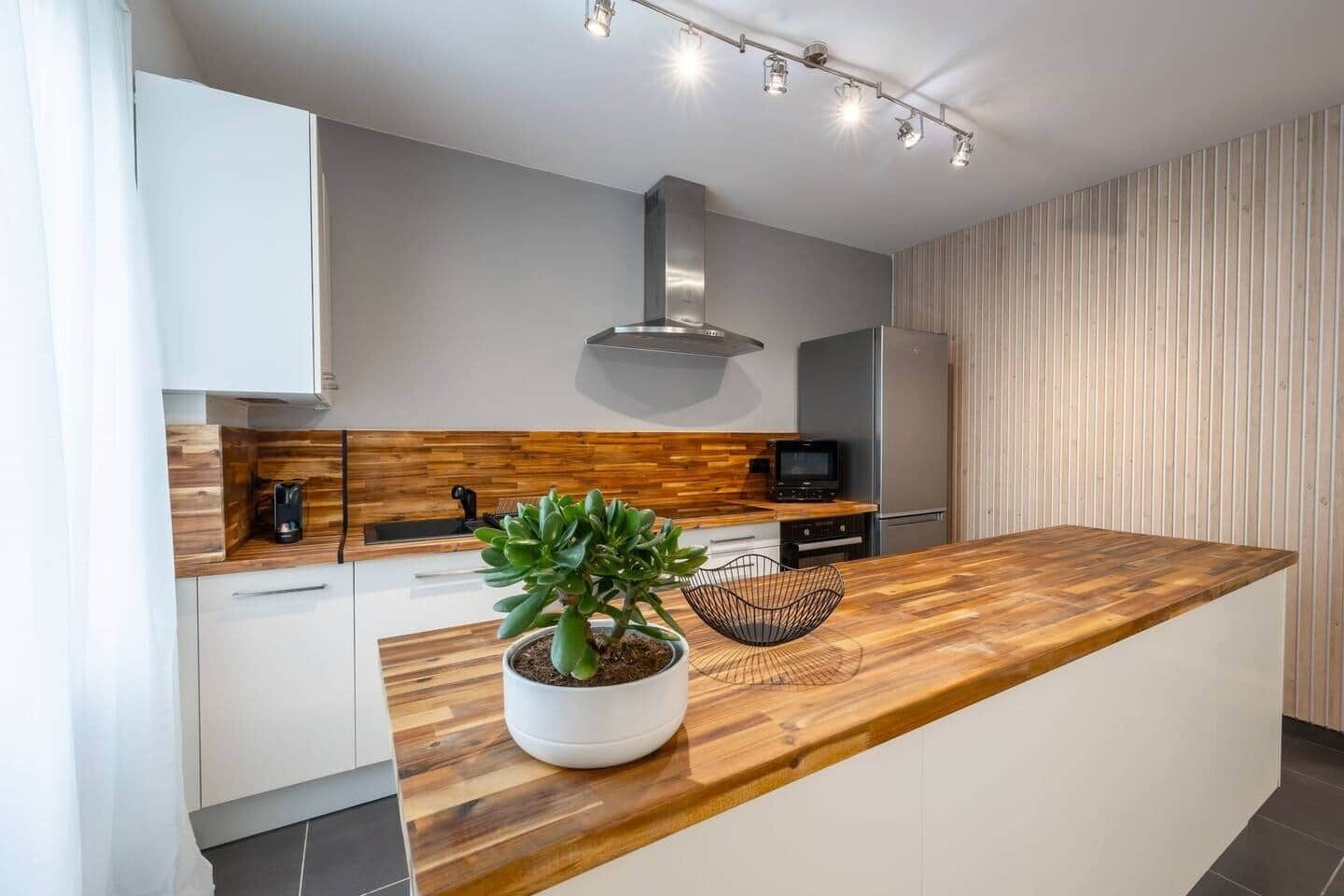 A modern kitchen with a wooden countertop, a built-in stove, and a stainless steel range hood.