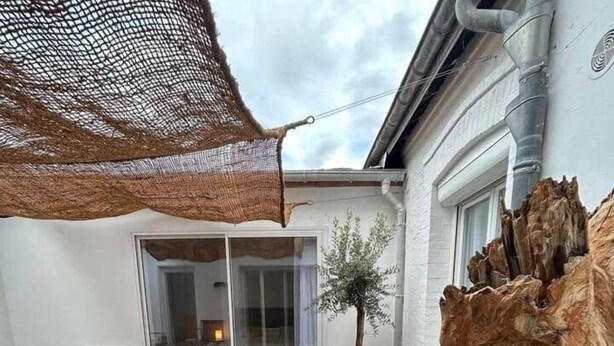 A wooden deck with lounge chairs, a large tree stump, and a mesh canopy. - To complete (Reims)