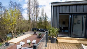 A modern outdoor deck with a dining area, a barbecue setup, and a large sliding glass door leading to a covered patio. - Loft Détente Fun Champagne Experience (Isles-sur-Suippe)