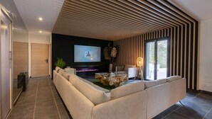 A modern living room with a large sectional sofa, a flat-screen TV, and a fireplace. - Loft Détente Fun Champagne Experience (Isles-sur-Suippe)
