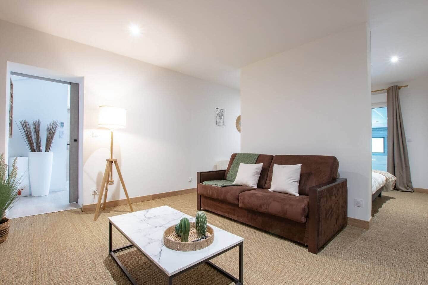 Ein Wohnzimmer mit einem braunen Sofa, einem weißen Couchtisch und einer Stehlampe.