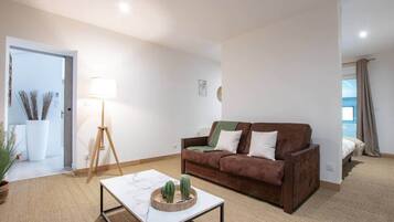 Ein Wohnzimmer mit einem braunen Sofa, einem weißen Couchtisch und einer Stehlampe.