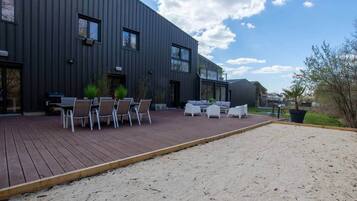 Un edificio moderno con un patio que tiene mobiliario exterior y una terraza de madera.