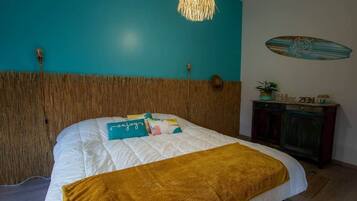 Une chambre à coucher comprenant un lit, une tête de lit, une table de chevet, une décoration sur le thème du surf et un luminaire suspendu.