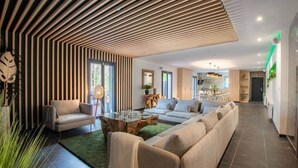 A modern living room with a sofa, armchairs, and a coffee table. There is a dining area in the background. - Loft Détente Fun Champagne Experience (Isles-sur-Suippe)