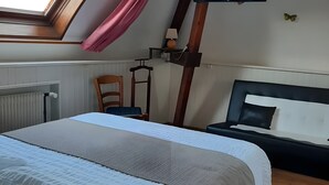 Un dormitorio con cama, escritorio, silla, televisor y ventana con cortinas.