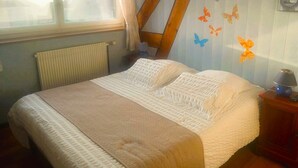 Un dormitorio con cama, ventana, radiador, viga de madera y adhesivos decorativos de mariposas.