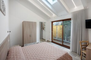 Een moderne slaapkamer met een groot bed, een kledingkast, een bureau en een televisie.