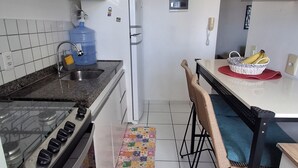 Eine kompakte Küche mit Gasherd, Kühlschrank, Spüle und einem Essbereich mit Tisch und Stühlen.