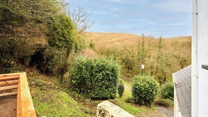 A garden with a wooden bench, stone wall, and a view of hills. - Host & Stay | Morley Cottage (Devon)