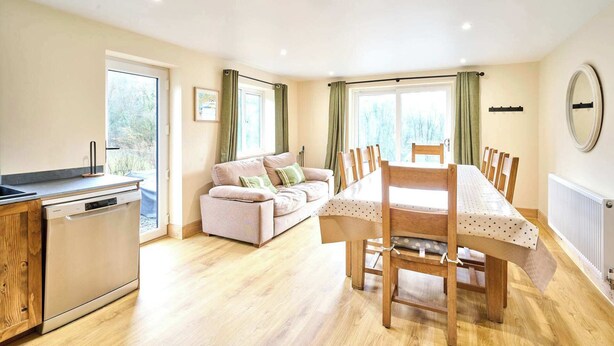 A spacious living area with a dining table, sofa, and kitchen area. - Host & Stay | Morley Cottage (Devon)