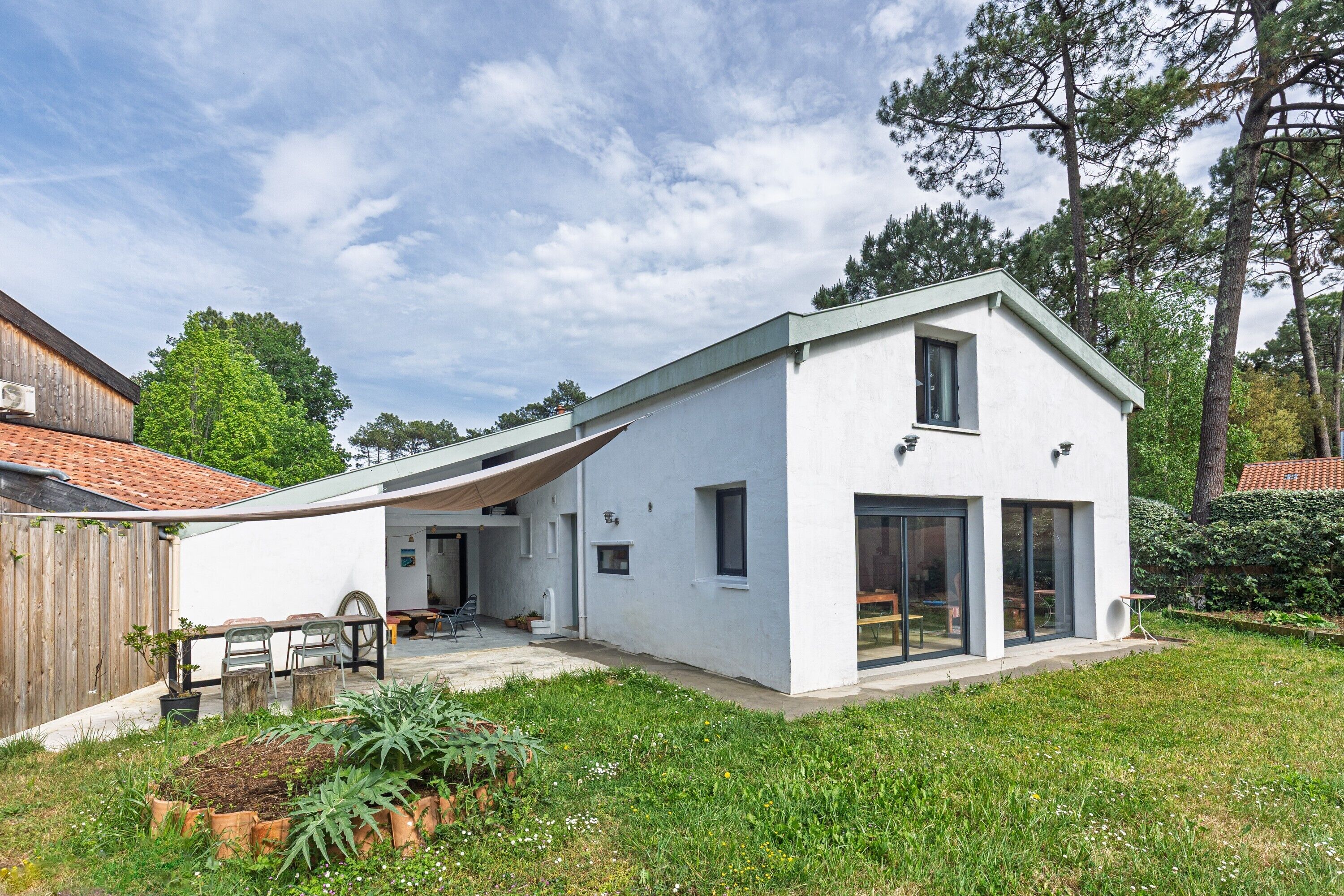 Una casa moderna con fachada blanca, techo inclinado y un patio cubierto.