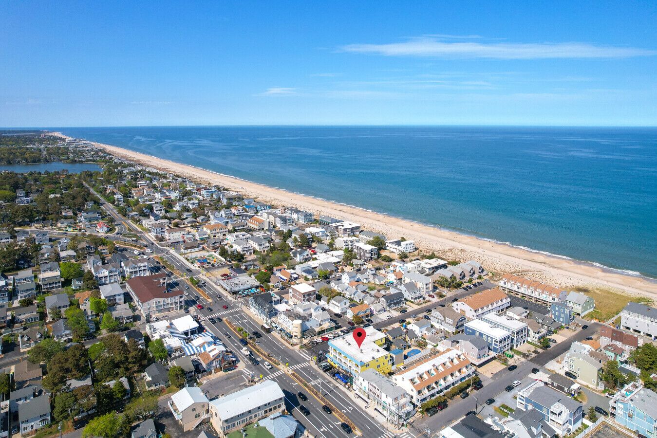 An aerial view of a coastal town with a beach, roads, and residential buildings.