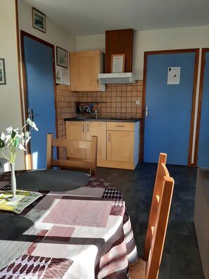 Een kleine keuken met houten kastjes, een ingebouwde kookplaat en een betegelde spatwand.