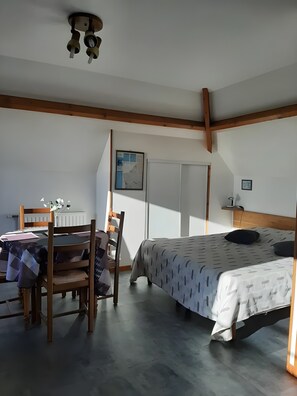 Een slaapkamer met een bed, een bureau en een stoel. Er hangt een kaart aan de muur en er is een radiator.