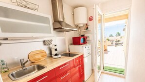 Cozinha moderna com pia, micro-ondas e armários vermelhos.