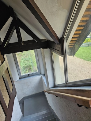 Un escalier donnant sur un jardin, visible à travers une fenêtre.
