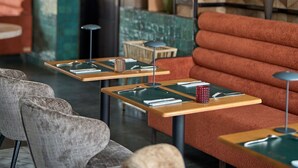 A modern lounge area with a herringbone-patterned wall, a wooden door, and a seating arrangement including a sofa and chairs.