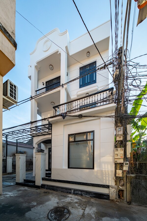 A two-story building with a balcony, a large window, and a gate. - An Dinh La Maison by Teky House (Thuan Hoa)