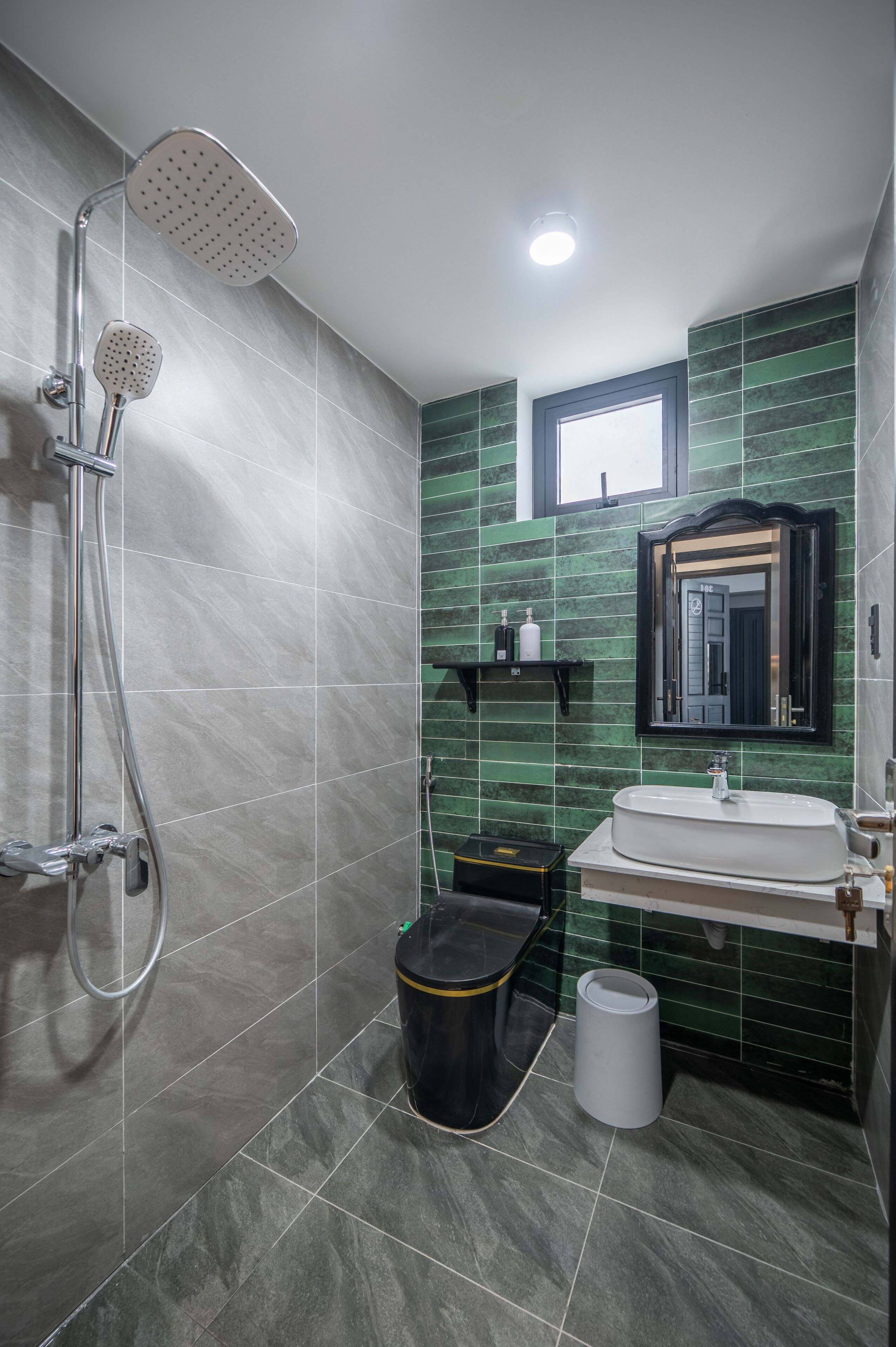 Une salle de bain avec une douche, un lavabo et des murs recouverts de carreaux verts.