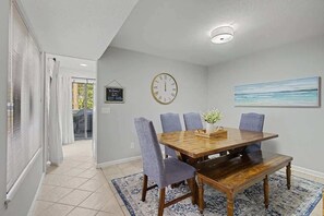 Un comedor con una mesa de madera, cuatro sillas, un reloj y un cuadro en la pared.