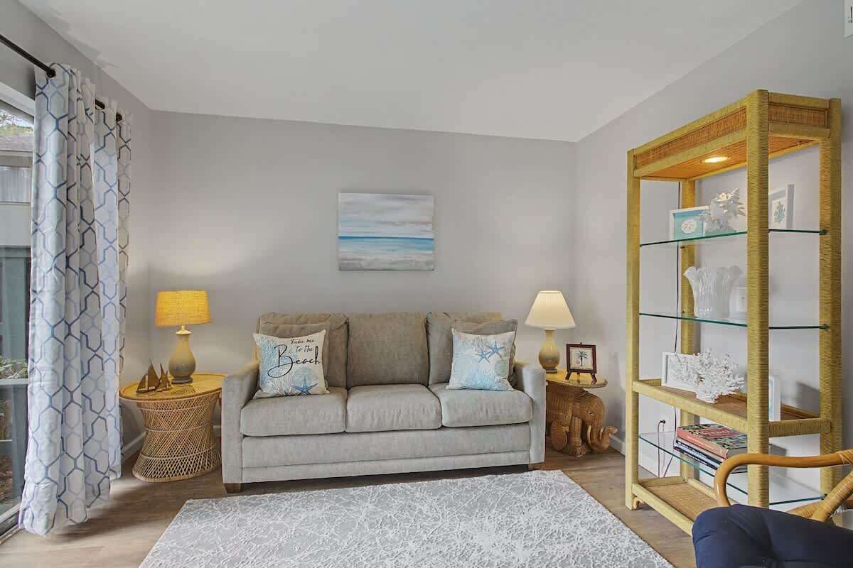 A living room with a sofa, two side tables, a bookshelf, and a patterned rug.