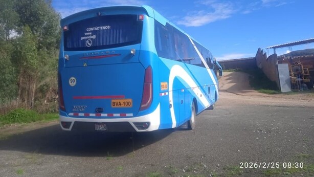 Een blauwe en witte bus geparkeerd aan de kant van de weg, met een heldere lucht.