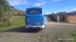Een blauwe bus geparkeerd aan een landelijke weg onder een heldere lucht.