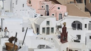 Un edificio blanco, muy poblado de balcones, con una destacada torre de campanas roja.