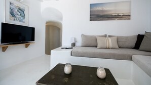 Una sala de estar moderna con una televisión de pantalla plana, un sofá, una mesa de centro con velas y un cuadro en la pared.