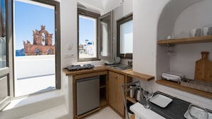 Cocina compacta con refrigerador incorporado, un lavamanos y un ventanal con vistas a un edificio de cúpula azul.