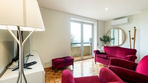 A modern living room with a red sofa set, a floor lamp, and a large window with a view of the city. - GuestReady - Charming Braga retreat (Braga)