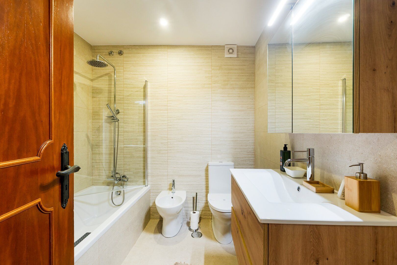A modern bathroom with a glass-enclosed shower, a white toilet, and a wooden vanity with a sink.