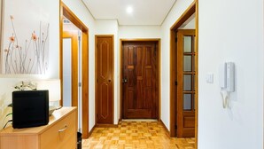 A hallway with wooden doors, a wall-mounted phone, and a desk with a computer. - GuestReady - Charming Braga retreat (Braga)