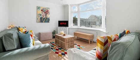Ett modernt vardagsrum med en soffgrupp, ett soffbord och en tv som visar ”NETFLIX”.