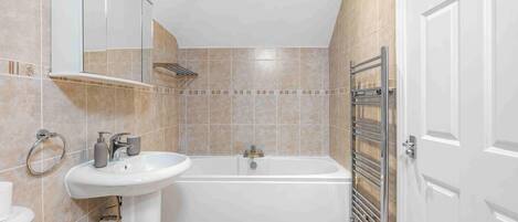 A modern bathroom with a bathtub, a sink, and a mirror.