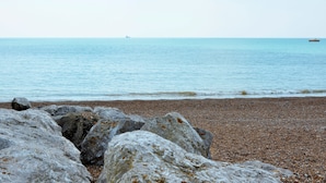 A rocky beach with calm sea and distant boats. - Sea Palm By My Getaways (Lancing)