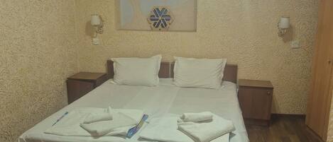 Un dormitorio con una cama grande, dos mesitas de noche, una lámpara de pared y un adorno mural.
